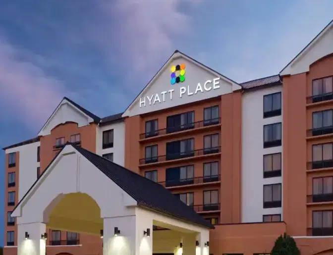 Exterior view of Hyatt Place Orlando Airport Hotel, featuring a tall terracotta building under a beautiful evening sky.