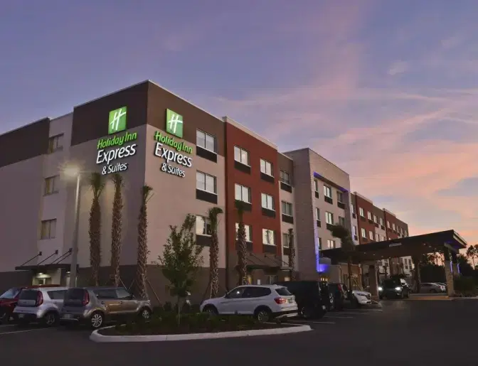 Exterior of Holiday Inn Express & Suites Orlando Southeast, a contemporary hotel offering comfort and convenience for travelers, featuring a sleek facade and landscaped surroundings.