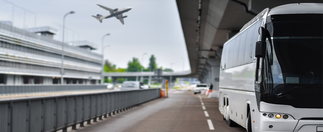 Shuttle bus parked at airport with airplane flying home in the sky