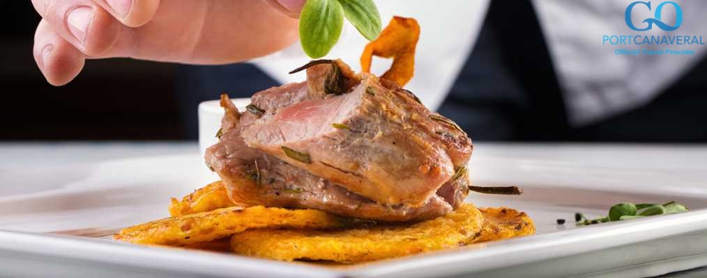 Chef in hotel or restaurant kitchen cooking, only hands. Prepared meat steak with potato or celery pancakes.He is working on the herb decoration.