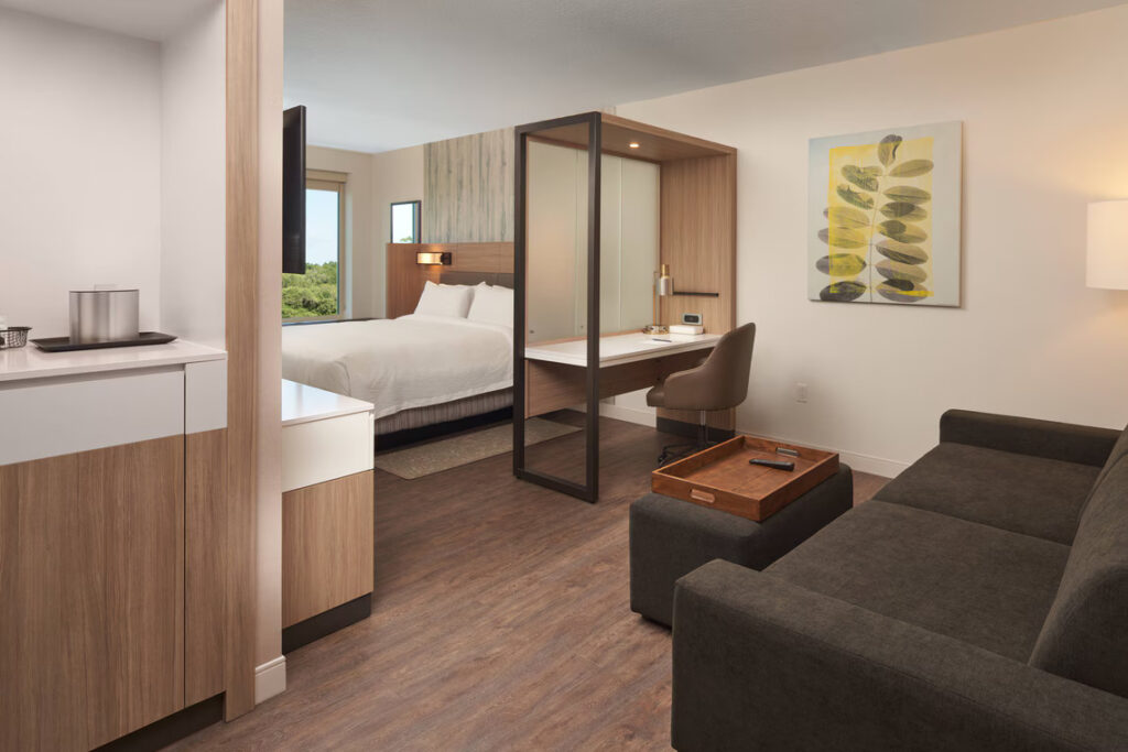 SpringHill Suites Lake Nona king bed hotel suite with room divider desk, ottoman and sleeper sofa