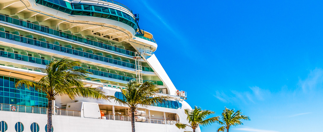 Cruise ship with many floors for cabins to choose docked at pier with palm trees. one of the cruise mistakes to avoid is picking a random cabin.