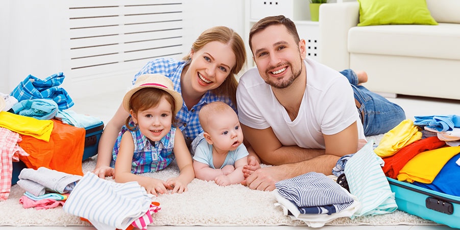 Family with young children surrounded by suitcases and clothing while packing for cruise