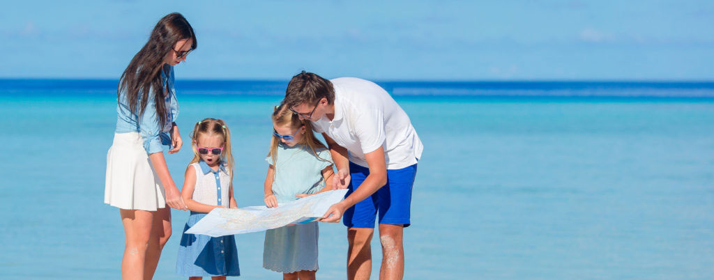 Happy family of four with map on the beach