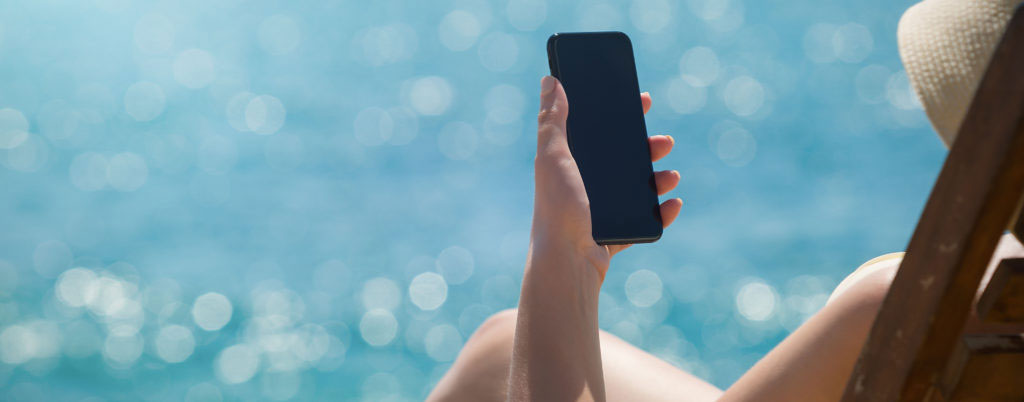 Young girl lying on a beach lounger with mobile phone in hand on the tropical island