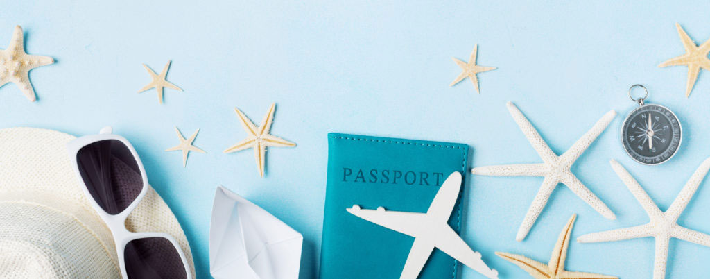 Summer holidays, vacation, travel and tourism background from sunglasses, hat, passport, airplane and boat miniatures, starfish. Top view. Flat lay.