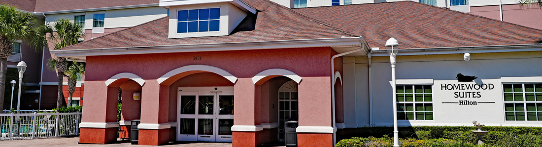 Exterior view of the entrance to Homewood Suites by Hilton Orlando Airport hotel with Port Canaveral shuttle