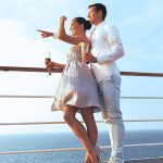 Couple standing by the balcony deck on the best cruise with the ocean in the background