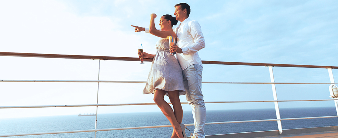 Couple standing by the balcony deck on the best cruise with the ocean in the background