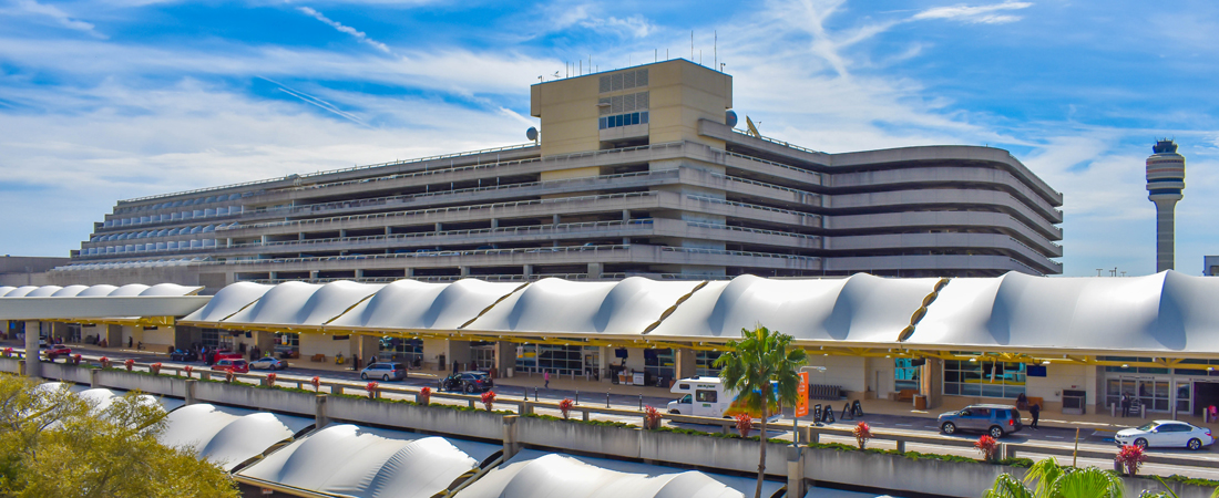 Cars waiting for guests fly into the Orlando Airport (MCO) terminal with parking garage in the background