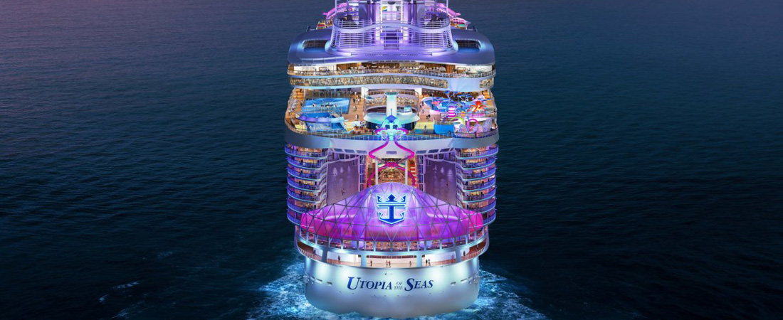 The back of Utopia of the Seas ship is lit up with lights, sailing in the open seas at night