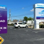 A Go Port parking lot in Port Canaveral during the day, with a shuttle bus ready to transport Carnival Mardi Gras passengers to the cruise terminal