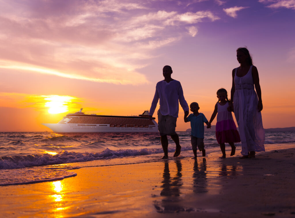 Family standing together on the beach at sunset, enjoying the warm glow over the ocean during their cruise vacation