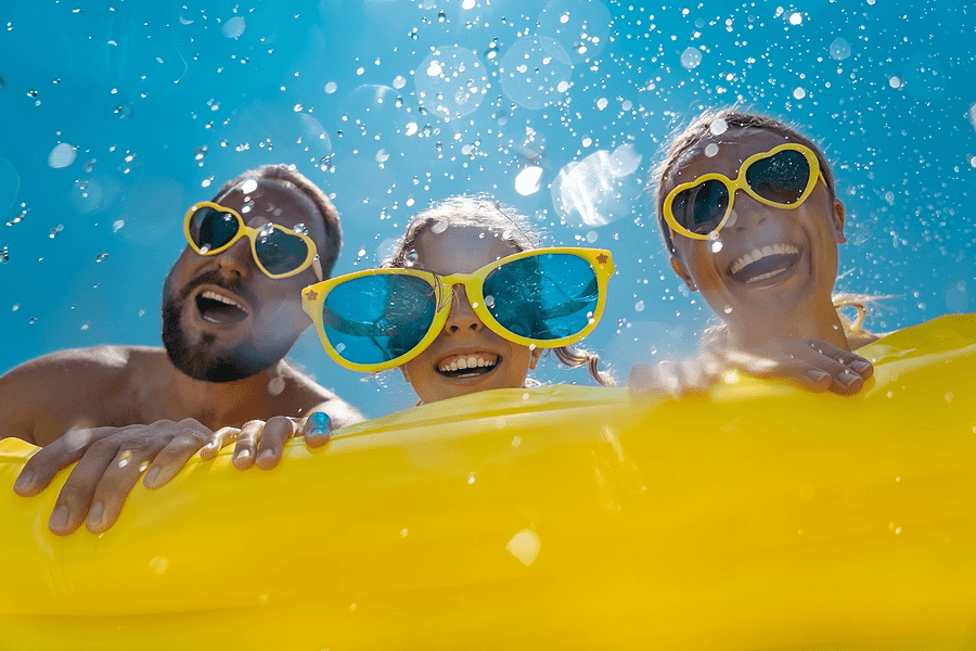 Family gathered around at beach, with big yellow sunglasses on