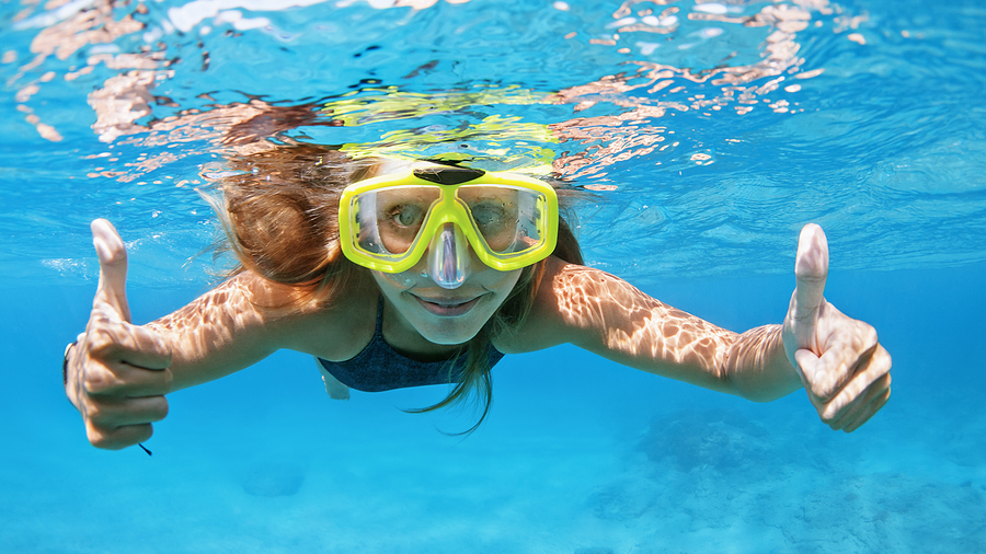 Woman underwater snorkeling, giving the camera a thumbs up