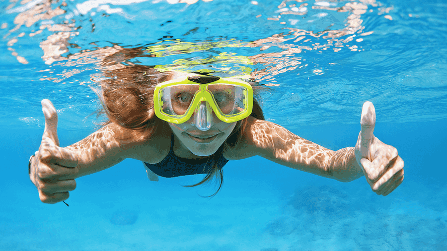Woman underwater snorkeling, giving the camera a thumbs up