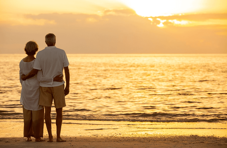 senior couple standing together on a beach.